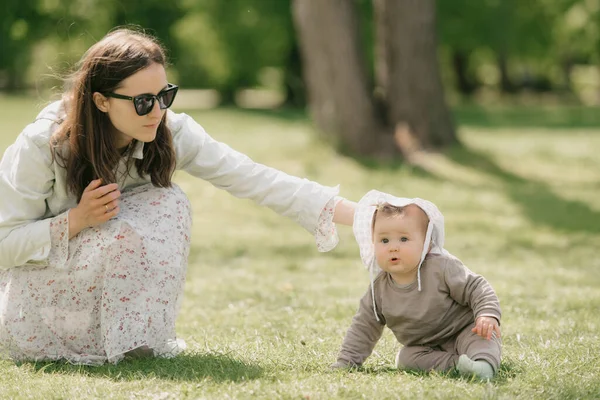 Una joven madre está jugando con su hija de 7 meses en la hierba. — Foto de Stock