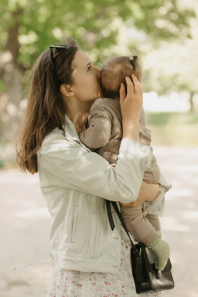 한 젊은 엄마 가 공원에서 7 개월된 딸을 안고 있습니다. — 스톡 사진