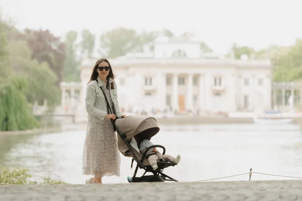 Matka pózuje se svým dítětem v kočárku na území paláce — Stock fotografie