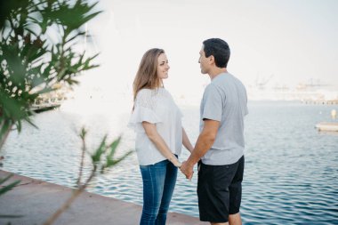 İspanyol tarzı bir adam, akşam İspanya 'daki iskelede gülümseyen esmer kız arkadaşının elini tutuyor. Valencia 'da randevusu olan iki turist..