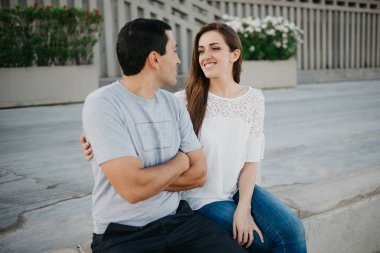 Gülümseyen esmer bir kız ve İspanyol erkek arkadaşı birbirlerine bakıp akşamları İspanya 'daki iskelede takılıyorlar. Valencia 'da gün batımında bir çift turist..