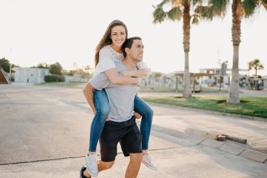 Gülümseyen esmer bir kız İspanya 'da avuçlarının arasında İspanyol erkek arkadaşına biniyor. Valencia 'da gün batımında bir çift turist..