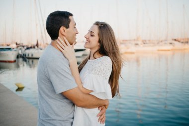 İspanyol bir adam akşamleyin İspanya 'da bir limanda mutlu esmer kız arkadaşının gözlerine bakıyor. Valencia 'da gün batımında birkaç turist yatların yanında çıkıyorlar..