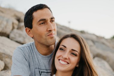 İspanya 'da bir dalgakıranın taşları üzerinde gülümseyen kız arkadaşına sarılan bir adamın yakın bir fotoğrafı. Valencia 'da gün batımında bir çift turist..