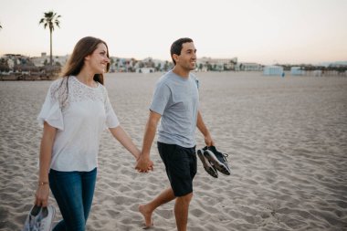 İspanyol bir adam ve gülümseyen kız arkadaşı akşam İspanya 'da kumlu bir plajda yürüyorlar. Bir çift turist Valencia 'da denize bakıyor..