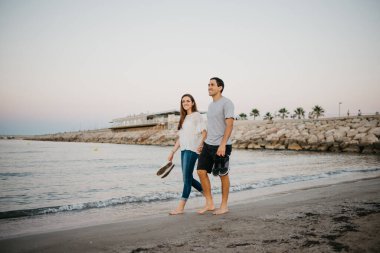 İspanya 'da, Balear Denizi' nin kıyısındaki kumlu bir sahilde çıplak ayakla dolaşan mutlu kız arkadaşıyla İspanyol bir adamın tam boy fotoğrafı. Valencia 'da randevusu olan iki turist.