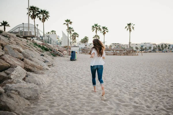 Akşam İspanya 'da dalgakıran taşlarının yanında plaj boyunca koşan bir kadının arkasından bir fotoğraf..