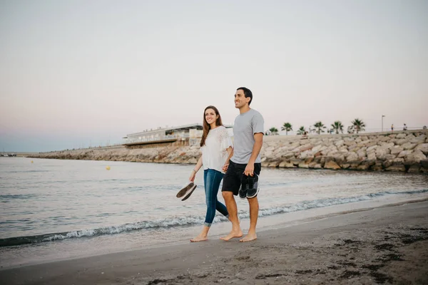İspanya 'da, Balear Denizi' nin kıyısındaki kumlu bir sahilde çıplak ayakla dolaşan mutlu kız arkadaşıyla İspanyol bir adamın tam boy fotoğrafı. Valencia 'da randevusu olan iki turist.