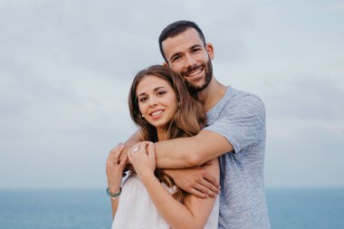 İspanya 'daki parkta esmer kız arkadaşının arkasından sarılan İspanyol bir adamın yakın bir fotoğrafı. Birkaç turist Valencia 'da gün batımında deniz kenarında poz veriyor..