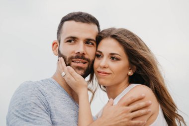 İspanya 'da bir dağ parkında kayalık deniz kıyısında birbirine sarılan İspanyol bir adamın ve gülümseyen kız arkadaşının yakın portresi. Valenci 'de bir çift mutlu turist