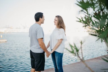 İspanyol tarzı bir adam, akşam İspanya 'daki iskelede gülümseyen esmer kız arkadaşının elini tutuyor. Valencia 'da randevusu olan iki turist..