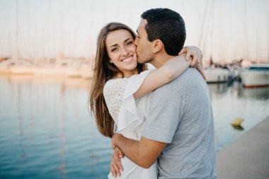 İspanyol bir adam akşamleyin İspanya 'da limanda mutlu esmer kız arkadaşına sarılıp öpüyor. Valencia 'da gün batımında birkaç turist yatların yanında çıkıyorlar..