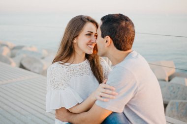 İspanyol bir adam, akşam İspanya 'da dalgakıranda gülümseyen esmer kız arkadaşına bakıyor. Valencia 'da gün batımında bir çift turist..