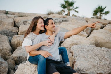 İspanyol bir adam kız arkadaşının bacaklarının arasında oturuyor ve akşamleyin İspanya 'da bir dalgakıranın taşlarının üzerinde. Bir kadın gün batımında kocasına sarılıyor. Adam Valencia 'yı işaret ediyor.