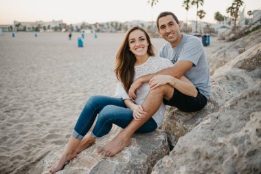 İspanya 'da bir dalgakıranın taşlarının üzerinde erkek arkadaşının bacaklarının arasında oturan bir kadın. Bir adam gün batımında karısına sarılıyor. Birkaç turist Valencia 'da poz veriyor..