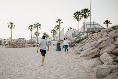 Akşamları İspanya 'da dalgakıran taşlarının yanında sahilde kız arkadaşına koşan bir adamın arkasından çekilmiş bir fotoğraf. Valencia 'da gün batımında bir çift turist..