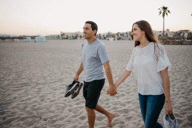 İspanyol bir adam ve gülümseyen kız arkadaşı akşam İspanya 'da kumlu bir plajda yürüyorlar. Bir çift turist Valencia 'da denize bakıyor..