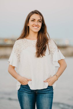 Genç bir kadın İspanya 'da alacakaranlıkta deniz kenarında kumlu bir sahilde poz veriyor. Valencia 'daki Balear Denizi yakınlarında bir kadın turist..