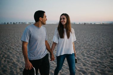 İspanyol bir adam ve gülümseyen kız arkadaşı akşam İspanya 'da Balearic Denizi yakınlarında kumlu bir plajda geziniyorlar. Valencia Alacakaranlık 'ta buluşan mutlu turistler..