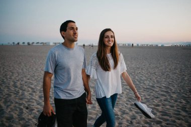 İspanyol bir adam ve gülümseyen kız arkadaşı akşam İspanya 'da Balearic Denizi yakınlarında kumlu bir plajda geziniyorlar. Valencia Alacakaranlık 'ta buluşan iki turist..