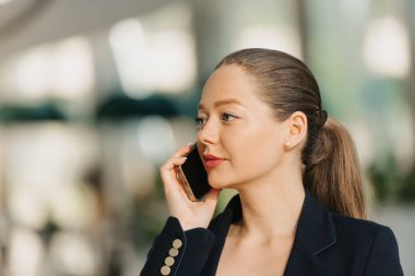 Telefonla konuşan bir emlakçının yakın bir fotoğrafı. - Ne? Modern lobideki bir kadının vesikalığı. Bir iş kadını ofisinden çağdaş bir iç mekanda ayrılıyor..