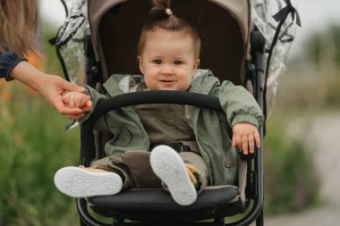 Bulutlu bir günde bebek arabasında bir bayan çocuk oturuyor. Yeşil bir köyde, yağmurluklu genç bir kız bebek arabasında. Bir anne kızının elini tutuyor..