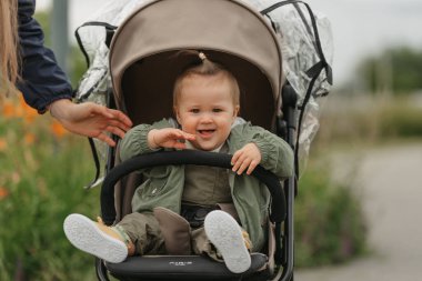 Dişi bir çocuk bulutlu bir günde bebek arabasında dinleniyor. Yeşil bir köyde, yağmurluklu güzel bir kız bebek arabasında şarkı söylüyor..