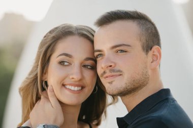 Romantik bir adam gülümseyen kız arkadaşını İspanya 'nın bir şehrinde günbatımında modern şehir mekanında tutuyor. Akşam Valencia 'da randevusu olan bir çift turist..