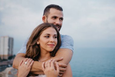 İspanya 'daki parkta esmer kız arkadaşının arkasından sarılan İspanyol bir adamın yakın bir fotoğrafı. Bir çift turist Valencia 'da gün batımında denize bakıyor..