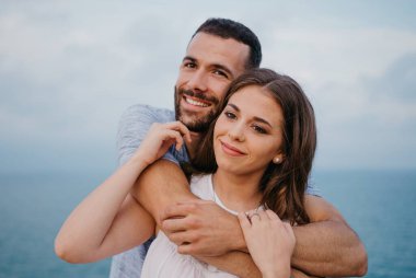 İspanya 'daki parkta esmer eşinin arkasından sarılan İspanyol bir adamın yakın bir fotoğrafı. Birkaç turist Valencia 'da gün batımında deniz manzarasının keyfini çıkarıyorlar..