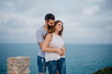 İspanyol bir adam akşamleyin İspanya 'daki parkta esmer karısının arkasından sarılıyor. Bir çift turist, Valencia 'da gün batımında deniz kenarında eğleniyorlar..