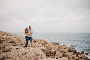 İspanyol bir adam ve Latin kız arkadaşı İspanya 'da bir dağ parkında kayalık deniz kıyısında sarılıyorlar. Valencia 'da iki turist eğleniyor..