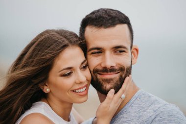 İspanya 'da bir dağ parkında kayalık deniz kıyısında birbirine sarılan İspanyol bir adamın ve gülümseyen kız arkadaşının yakın portresi. Valenci 'de bir çift mutlu turist