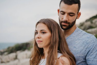 İspanya 'nın kayalık deniz kıyısında Latin bir kız arkadaşına sarılan İspanyol bir adamın yakın portresi. Akşamları Valencia 'daki bir dağ parkında birkaç turist..