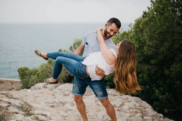 一位西班牙裔男子将他的拉丁女友抱在怀里 背景在西班牙的一个高地公园里 瓦伦西亚的日落时分 几位游客在海边玩得很开心 — 图库照片