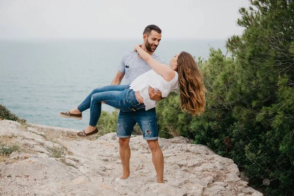 一位西班牙裔男子将他的拉丁女友抱在怀里 背景在西班牙的一个高地公园里 两个游客在瓦伦西亚海边玩得很开心 — 图库照片