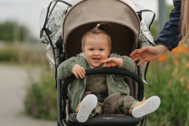 Dişi bir çocuk bulutlu bir günde bebek arabasında dinleniyor. Yeşil bir köyde, yağmurluklu güzel bir kız bebek arabasında şarkı söylüyor..