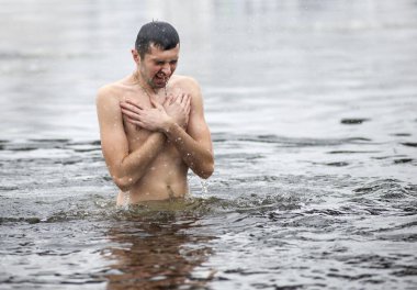 Kyiv, Ukraine - January 19, 2018 - A young man dips in the cold water of Dnipro River in Kyiv during the celebration of Epiphany