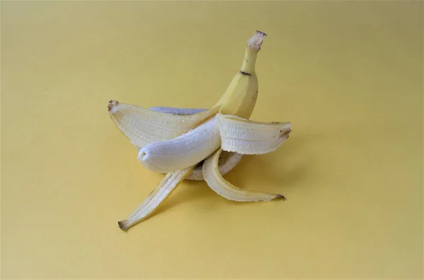 Sarı zemin üzerinde soyulmuş muz, minimalizm
