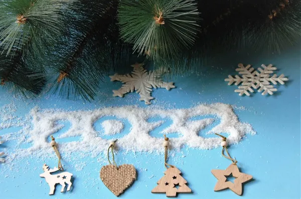 Vue de dessus d'une branche d'un arbre de Noël et des flocons de neige et des décorations naturelles, numéros 2022 de flocons de noix de coco sur un fond bleu. pose plate — Photo