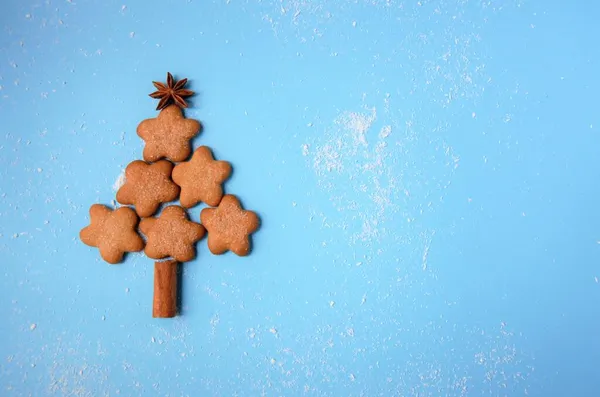 在蓝色的背景上有一棵由饼干、肉桂和八角茴香制成的圣诞树 — 图库照片