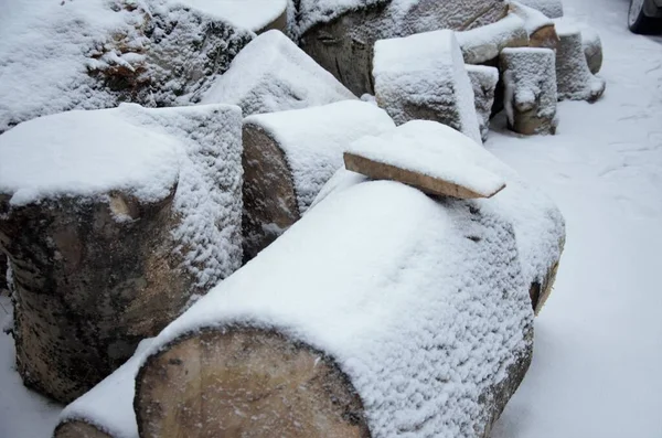 Shaft stack of large tree trunks covered with snow outdoors on a bright cold winter day, abstract background. Pieces of firewood. Wooden stack in a winter landscap — Stock Photo, Image