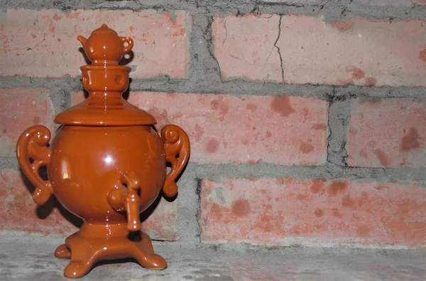 Toy ceramic samovar on a brick wall background — стоковое фото