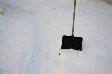 snow shovel stuck in snowdrift after cleaning
