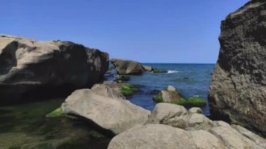 Büyük taşları ve mavi denizi olan deniz kenarında.