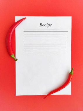 Kırmızı arkaplanda kırmızı biber ve tarif için bir yaprak.