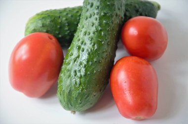 Salatalıklar ve domatesler beyaz arka planda yakın plan