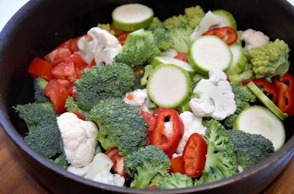 Groente in een koekenpan, bloemkool, broccoli, courgette en tomaat, bereiding voor het bakken Stockfoto