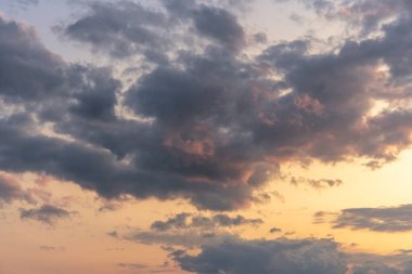Pembeyle parlayan güzel bulutlar batan güneşten turuncuya boyanmış bir gökyüzünde