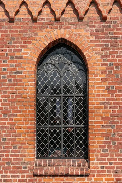 装飾されたガラスの棒とアーチ型の窓のある古いオレンジと赤のレンガの壁 — ストック写真
